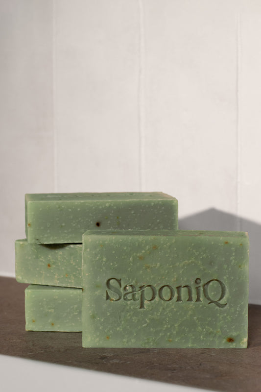 Green soap bars with 'SaponiQ' branding on a marble surface.