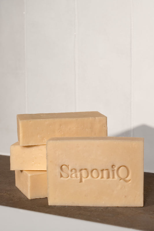 Cream colored bars of soap with 'SaponiQ' branding on a marble surface.